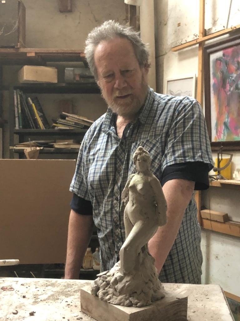 Simon Britton in his studio with a clay figure he is modelling